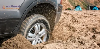 A cars tire spins in sand, illustrating the challenge of getting an unstuck car from the mud.
