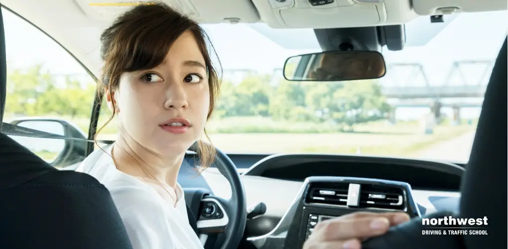 A young woman looks back while driving, embodying confidence in her journey of Becoming A Brilliant Driver.