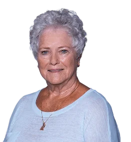 Smiling older woman with short, curly gray hair, wearing a light blue top and a necklace.