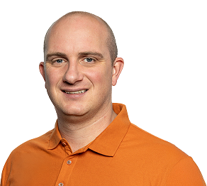 Smiling man with a shaved head wearing an orange polo shirt against a plain background.