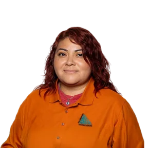 A woman with wavy red hair smiles, wearing an orange shirt with a triangular logo on the left side.