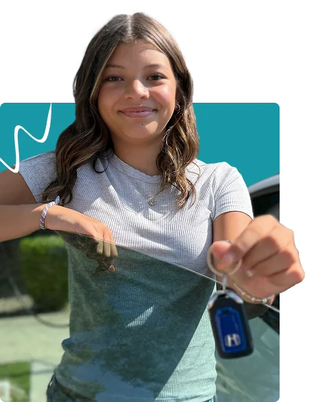 Smiling new driver standing beside a car and holding car keys after completing driving lessons