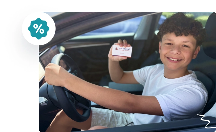 A smiling boy in a car holds a card, showcasing excitement and achievement.
