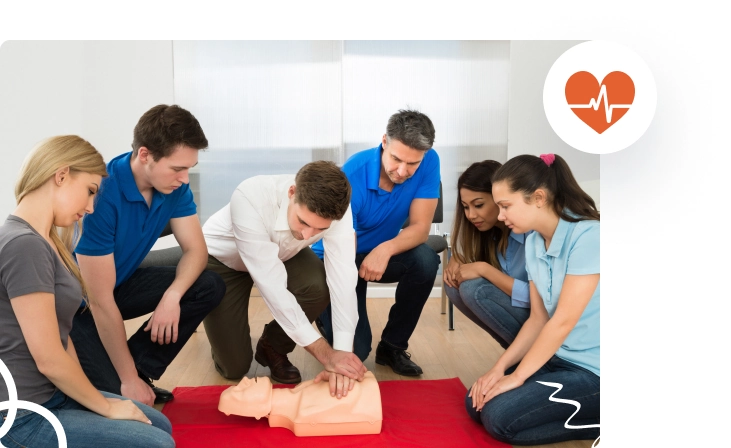 A group of six people practicing CPR on a manikin in a training session.