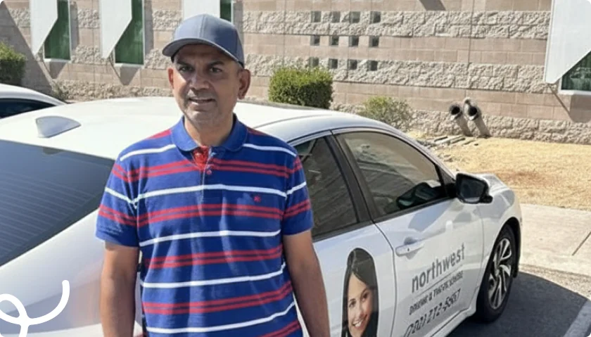 A man in a striped shirt and cap stands next to a car with a business advertisement on it.